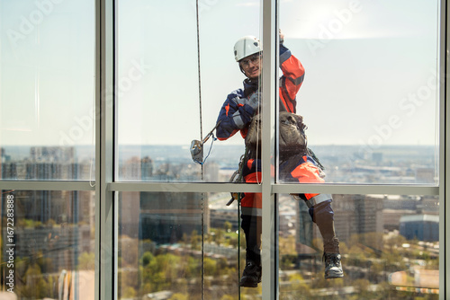Man industrial climber or window cleaner on a rope washing skyscraper windows.