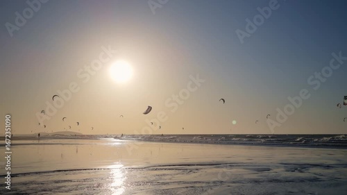 Kitesurfers gliding over the ocean during sunset.