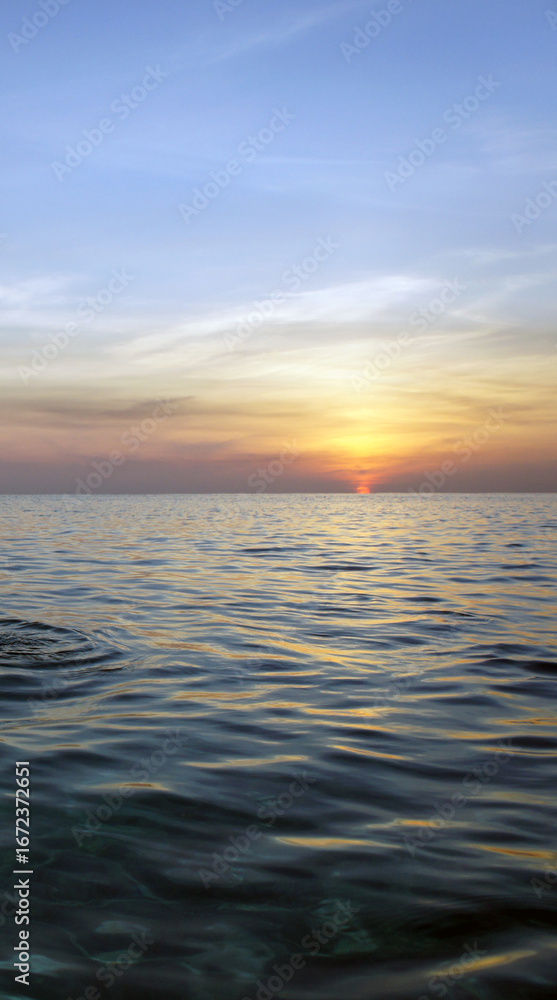 Obraz premium Golden sunset ocean scene with gentle waves and circular ripple under glowing sky