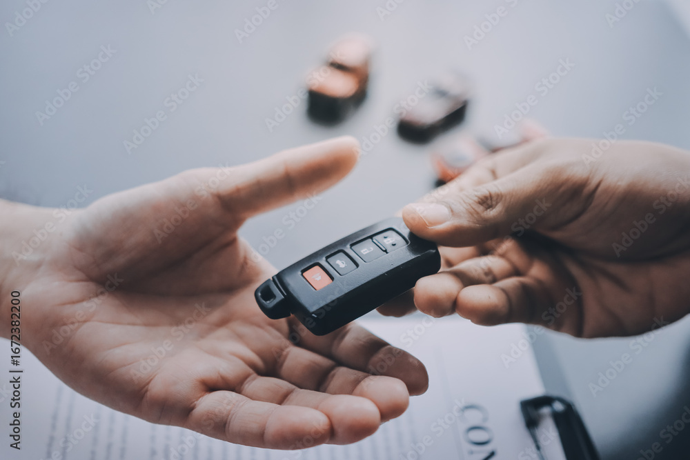 Fototapeta premium Car salesman gave the keys to the customers who signed the purchase contract legally, Successful completion of car sales, Purchase contract and key delivery.