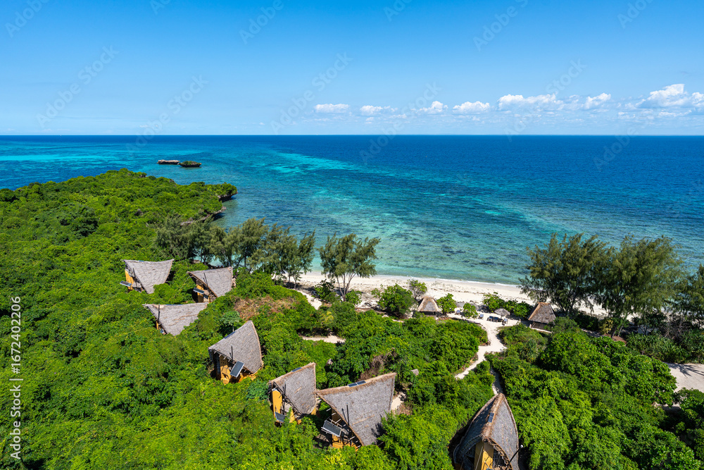 Fototapeta premium Eco bungalows nestled in the lush greenery of tropical Chumbe Island, Zanzibar, overlooking the turquoise waters of the Indian Ocean.