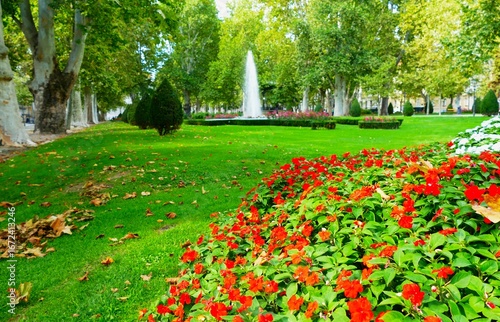City park with trees fountain and red flowers in full bloom, Zagreb, Croatia