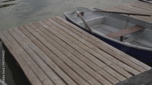 A serene and picturesque view of rowboats peacefully lined up along a rustic wooden dock by the glistening water