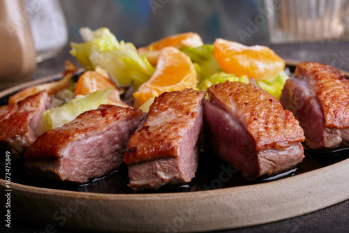 Fotografie Sliced seared duck breast with salad and orange sauce.