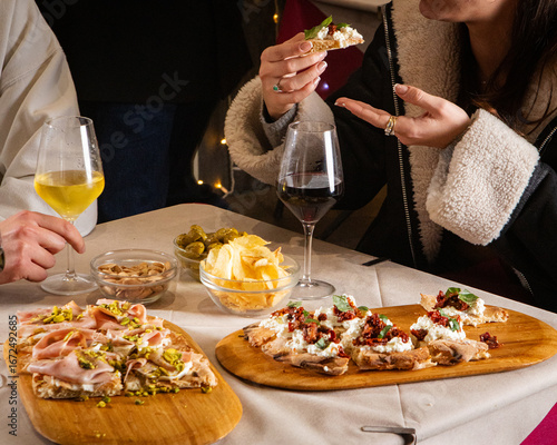 At a lively bar table, unseen guest enjoy food and drinks—cocktail, pinsa, and small bites fill the scene with flavor, conviviality, and Italian aperitivo vibes.