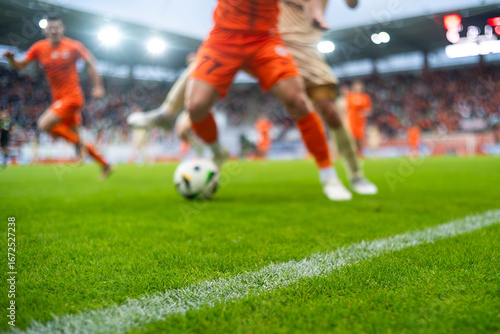 grass and sideline on the football pitch at the stadium and player's legs at the background