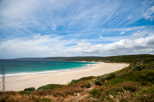 Crystal clear wave breaking on the sandy beach of Yallingup, Western Australia, with cliffs in the background