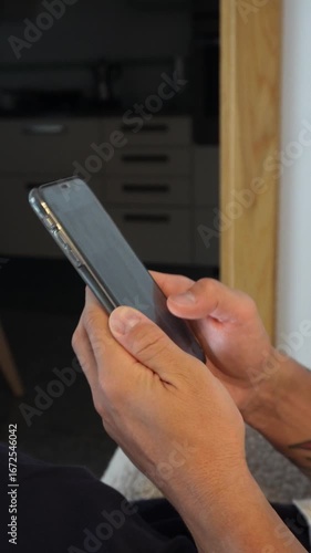 Scrolling on smartphone – vertical video. Man Hands holding smartphone and scrolling through social media app feed. Vertical 9:16 close-up of natural finger gestures, digital interaction