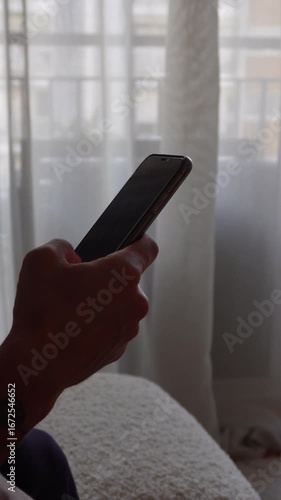 Scrolling on smartphone – vertical video. Man Hands holding smartphone and scrolling through social media app feed. Vertical 9:16 close-up of natural finger gestures, digital interaction