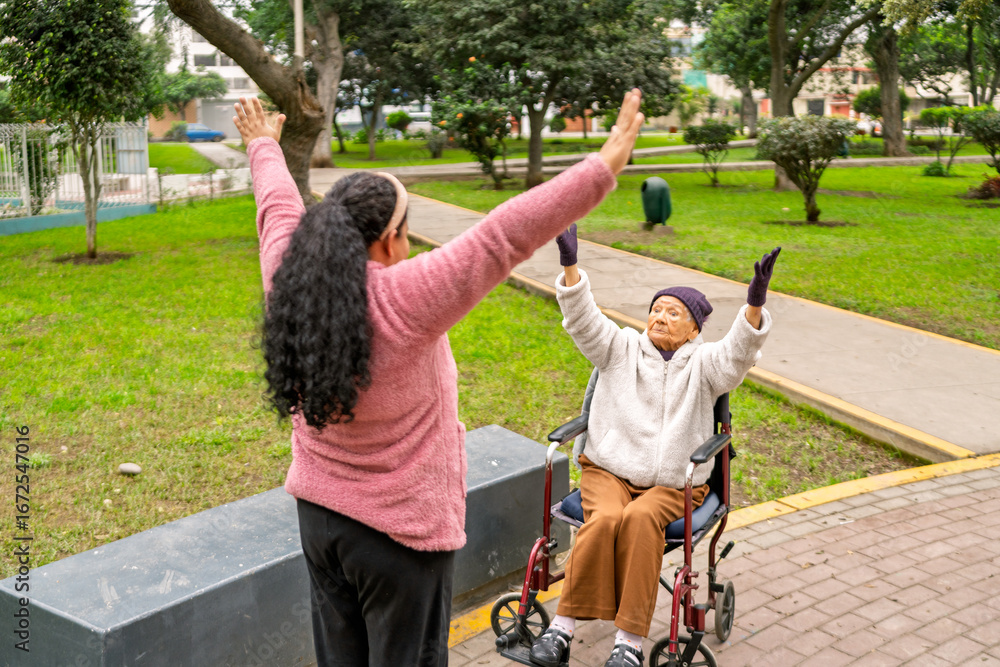 Obraz premium Nurse assisting elderly woman in wheelchair doing physical exercises in park