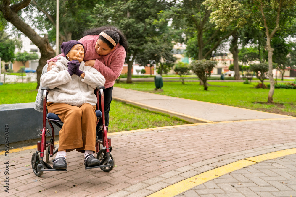 Fototapeta premium Nurse assisting elderly woman in wheelchair in park