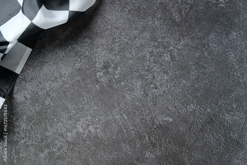 Naklejka premium Checkered racing flag draped over textured asphalt surface