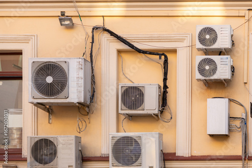 group of air conditioners is mounted on the wall of the building. cooling in hot weather, technologies for adjusting the temperature in the house. climate and weather conditions.