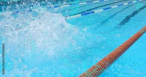 Male swimmer initiating dive headfirst into clear blue lane launching splash for sports training