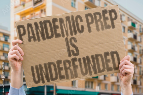 Wallpaper Mural "Pandemic prep is underfunded" on a protest banner highlighting systemic failures in readiness.PUBLIC. HEALTH. PREVENTION. GOVERNMENT. NEGLECT. CRISIS. RESILIENCE. Torontodigital.ca