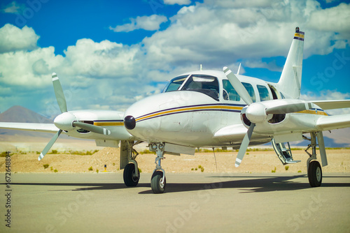 A close up of a Piper PA 31 Navajo, a light twin engine aircraft, on the tarmac under a blue sky.