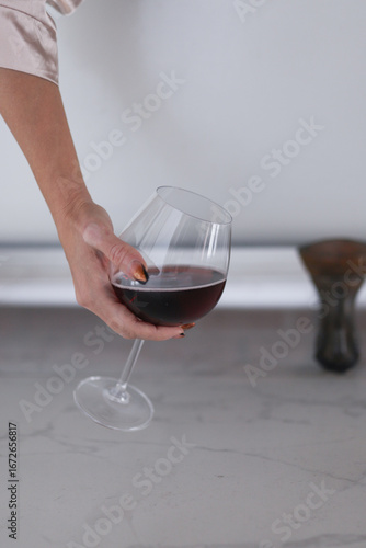Minimalistic lifestyle shot of a hand with manicured nails holding a glass of red wine. Elegant, sophisticated, and perfect for concepts of relaxation, celebration, or luxury.