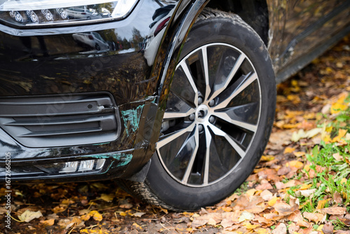 A parked vehicles tire and wheel in an autumn rural setting or urban cityscape. Ideal for transportation-related visuals with a focus on automotive exterior details.