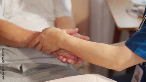Male caregiver holding senior man hands and consoling with empathy. Doctor or nurse visit and take care elderly patient at nursing home. Home medical healthcare service and health insurance.