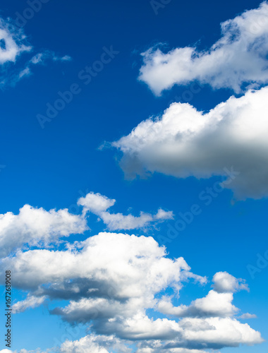 Fluffy white clouds floating in clear blue summer sky