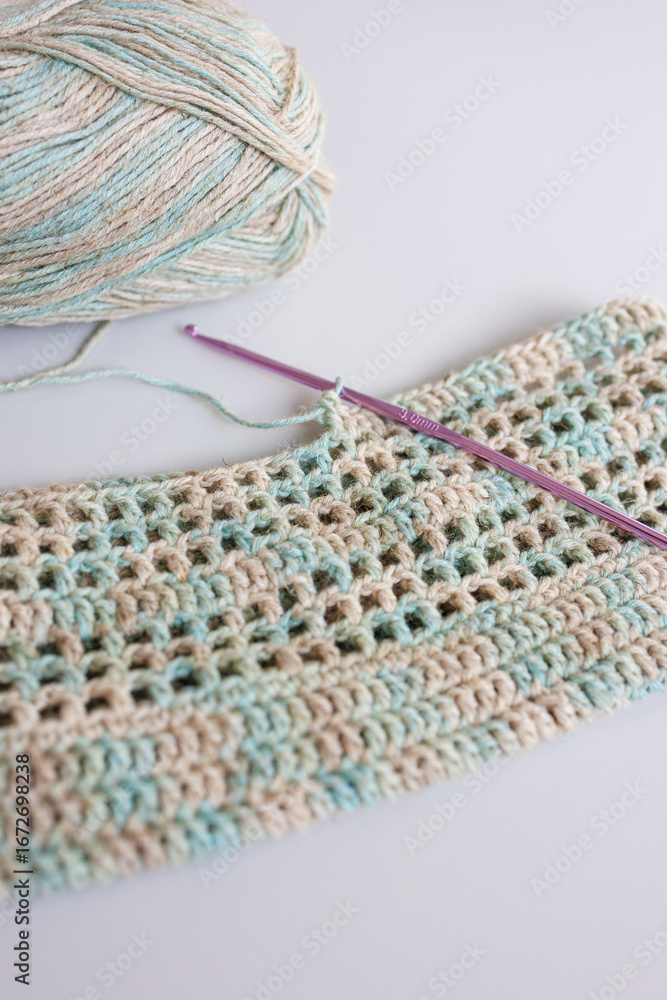Obraz premium Ball of yarn with crochet hook and handmade fabric in pastel colors
