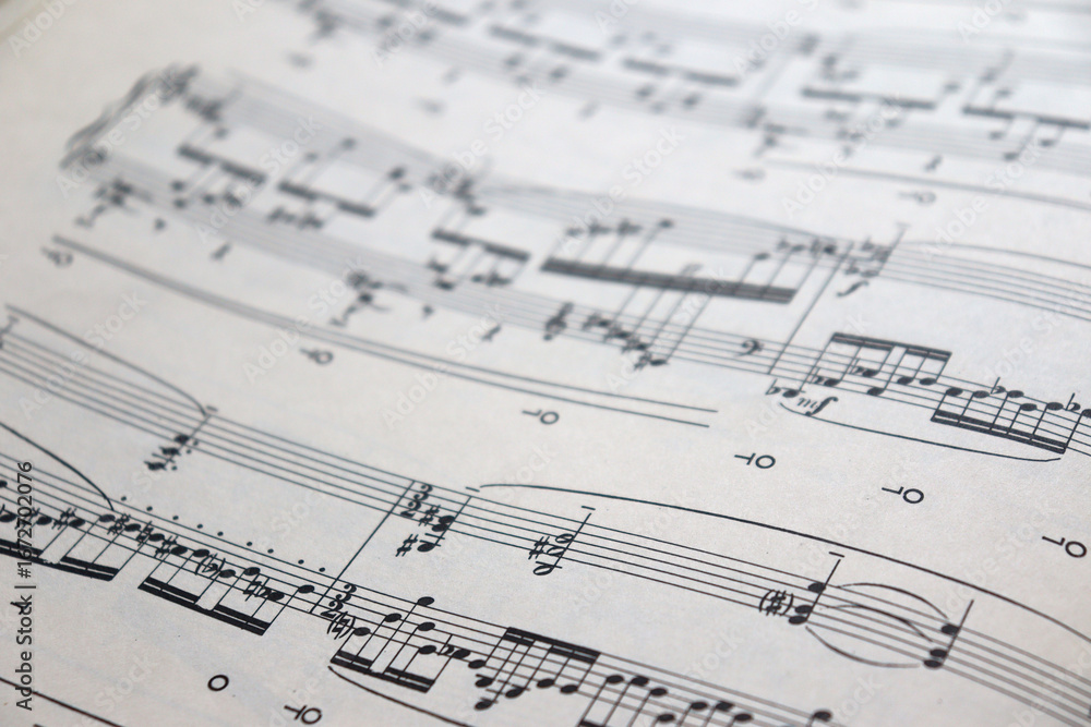 Fototapeta premium A white sheet with a musical partition. Musical notes on a sheet of music paper. Music notes as background with a close-up view.