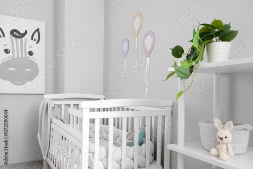 Baby crib near light wall i...