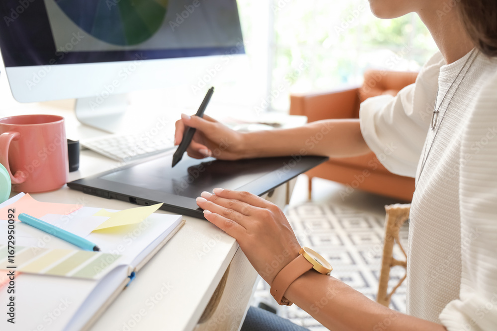 Fototapeta premium Female graphic designer working at table in office, closeup