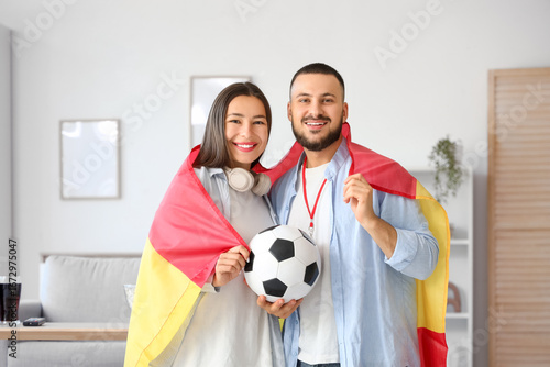 Young couple with flag of Spain watching football at home