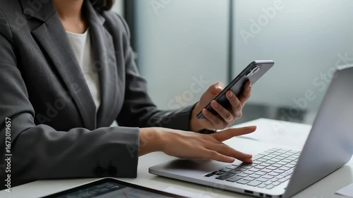 Business professional working on laptop and phone in office setting