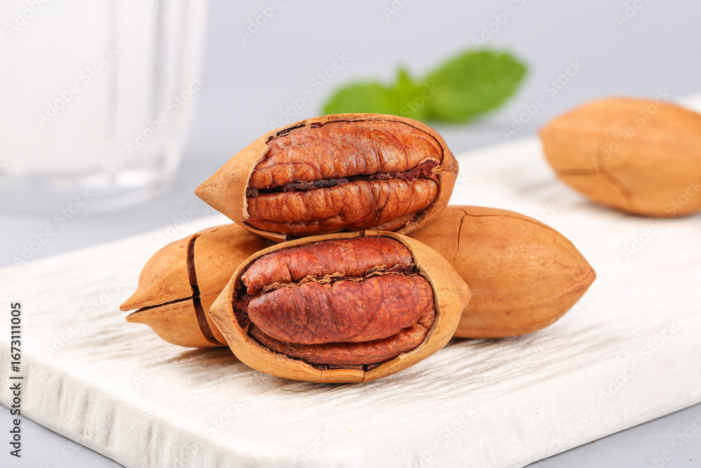 Obraz premium Fresh Pecan Nuts in Shells on White Wooden Board - Healthy Snack Food Studio Photography