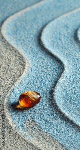 Amber stone on a textured sand surface with flowing patterns