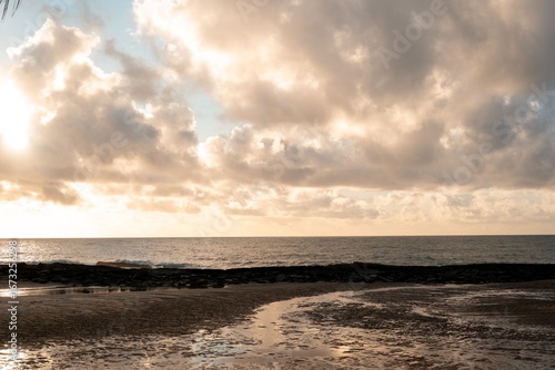 Serene coastal scene with dramatic clouds and sunlight over a tranquil sea at dawn