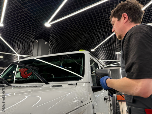 Foto Automobile special workers replacing windscreen or windshield of a car in auto service station garage