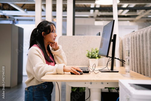 Woman working at computer in modern office workspace side view