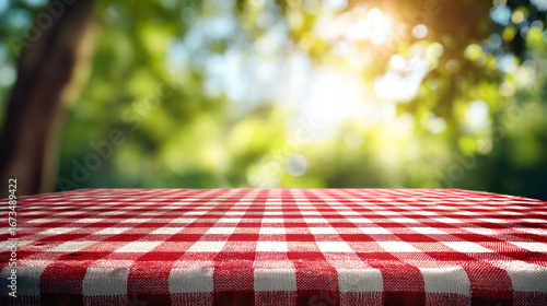 Red and white checkered tablecloth on a table with a blurred green background of trees and sunlight.