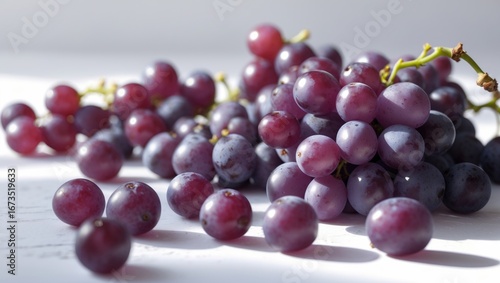 Clusters of red grapes on a white surface, fresh and ripe, with some grapes scattered around.