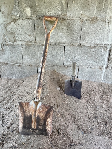 A shovels are stuck in a pile of sand.