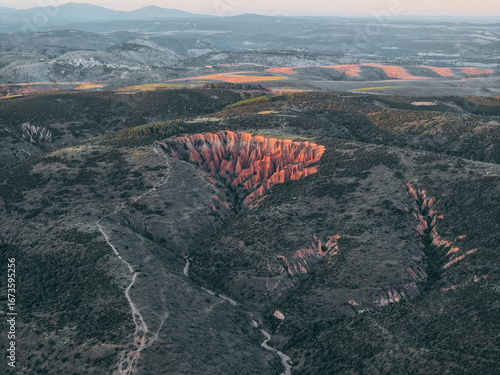 Aerial view of the dramatic Carcavas landscape, a geological wonder carved by erosion, casting long shadows in the warm light, ValdepeÃ±as de la Sierra, Castile-La Mancha, Spain.