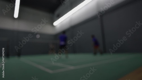 Blurry Action Shot From Badminton Match, The blurry action of a fierce badminton rally under bright lights, perfect for a dramatic sports movie scene.