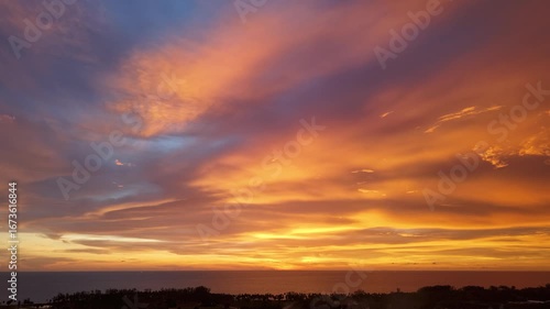 A breathtaking scenic panoramic view of a stunning sunrise, as vibrant hues of orange, pink, and gold blend to create a mesmerizing spectacle in the sky.