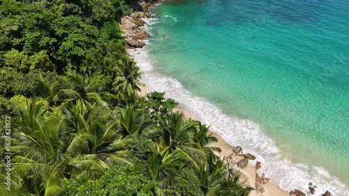 An aerial view of a serene tropical beach, where the lush green vegetation meets the crystal-clear turquoise water, creating a picturesque and relaxing scene. 