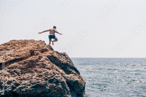 Принти на полотні Man in swimsuit jump from large stone cobblestone into water pond sea on summer
