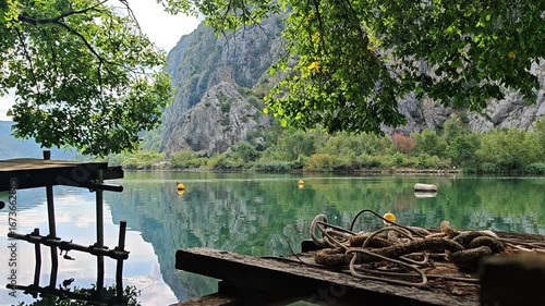 Peaceful Cetina River canyon with mountain reflections, old wooden dock and ropes