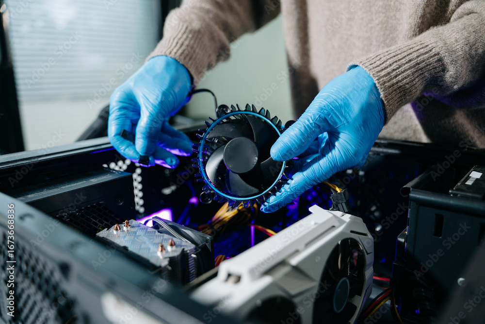 Naklejka premium Closeup of technician in gloves holding CPU cooler and heat gun over desktop PC. Ideal image for computer repair, cooling system, and hardware