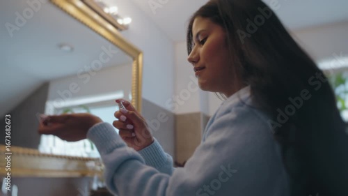 Latina Woman Applying Perfume in Bathroom Mirror Before Going Out