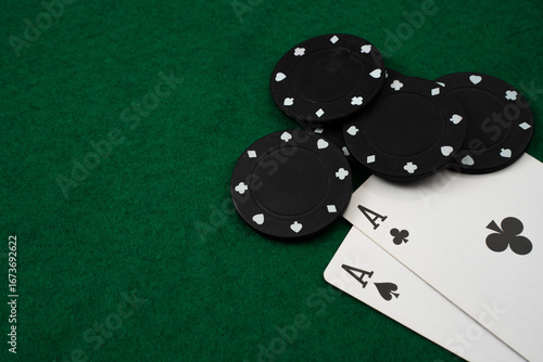Fotografie A poker game is taking place with four black chips and two aces on a green felt table