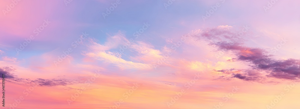 Fototapeta premium Sky with a soft pastel blend of pink, purple, and blue hues, illuminated by the golden light of sunrise or sunset, with wispy clouds scattered across the expansive canvas