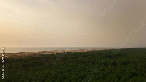 Luftaufnahme eines Sonnenuntergangs mit Drohne an der Atlantikküste in Frankreich, Ozean im Hintergrund, feuchte Luft, diesiger Himmel, späte Dämmerung