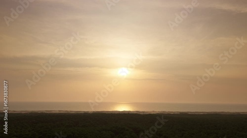 Luftaufnahme eines Sonnenuntergangs mit Drohne an der Atlantikküste in Frankreich, Ozean im Hintergrund, feuchte Luft, diesiger Himmel, späte Dämmerung